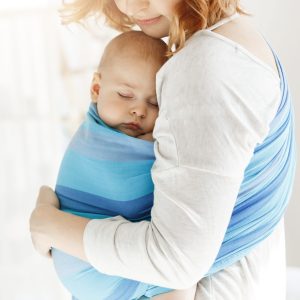 Tiny newborn child close eyes and having good sleep in baby slim feeling protection from his beautiful young mother. Family, lifestyle concept
